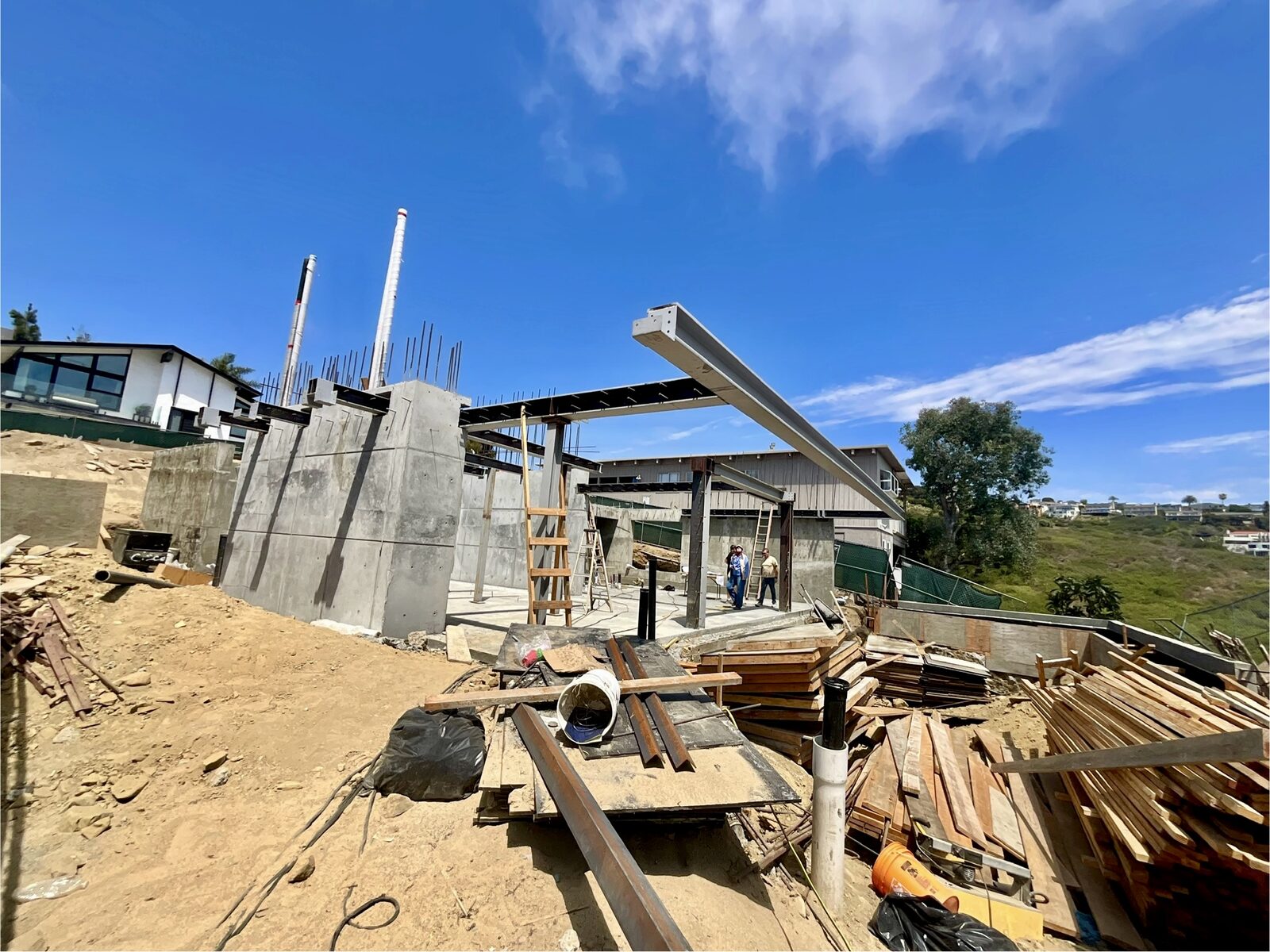 Wide flange beam being set over the concrete walls at the Bonita Way custom home